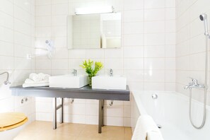 A modern bathroom with two sinks, a large bathtub, and a shower.