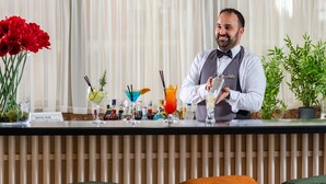 Una zona de bar con un cantinero, una variedad de bebidas y un letrero que indica que es el bar del hotel.