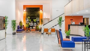 Un vestíbulo moderno con mostrador de recepción, zona de estar y escalera.