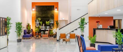 A modern lobby with a reception desk, seating area, and a staircase.