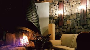 Una sala de estar acogedora con una pared de piedra, una chimenea y un sofá.