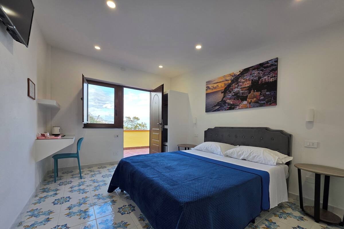 Un dormitorio con cama, escritorio, silla y un cuadro en la pared.
