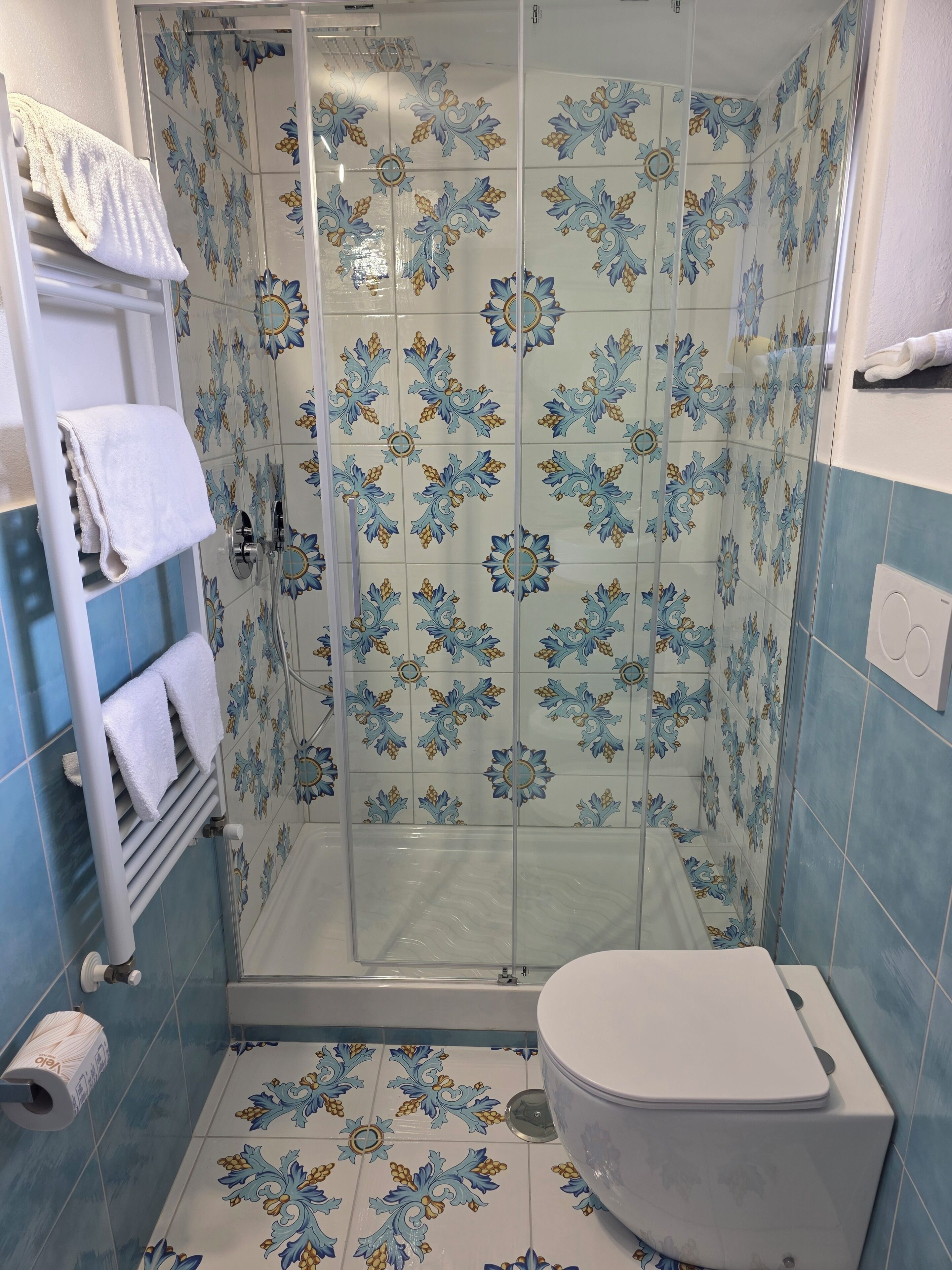 Un baño con ducha, inodoro y toallero.