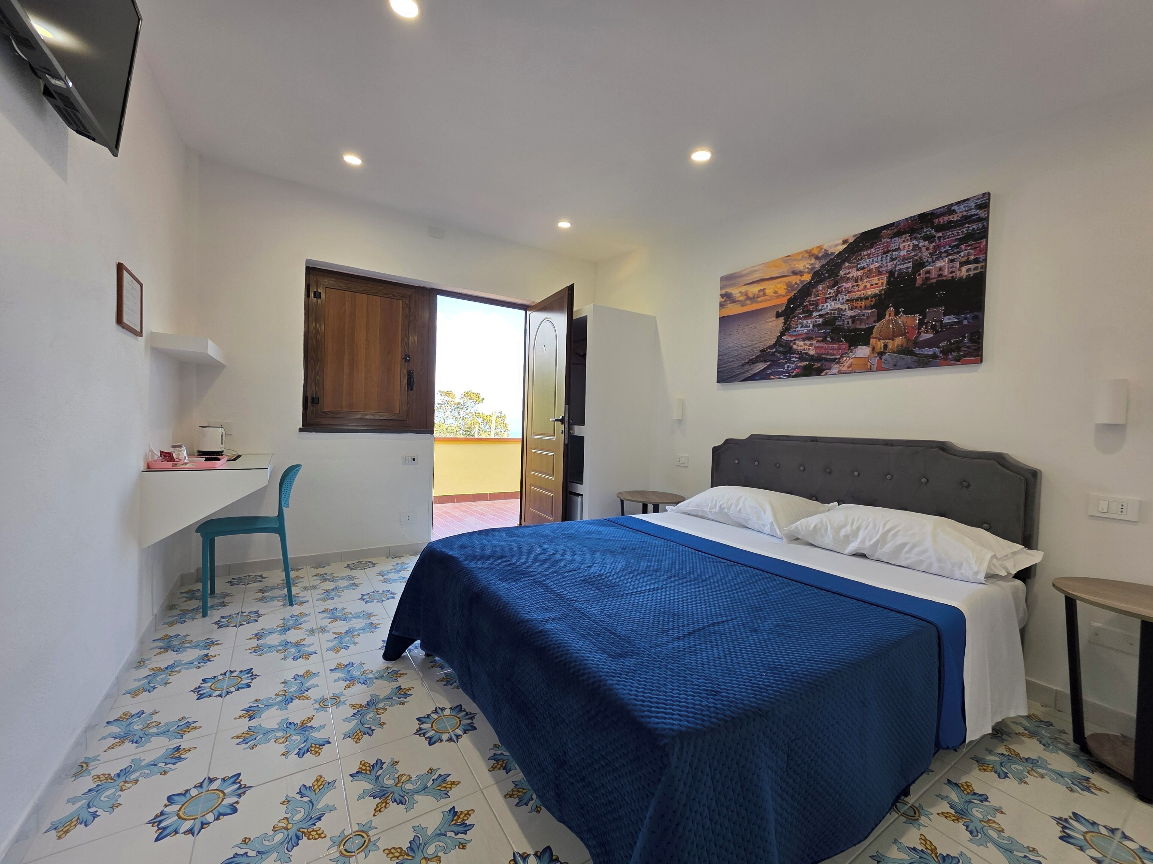 Une chambre à coucher avec un lit, un bureau, une chaise et un tableau au mur.