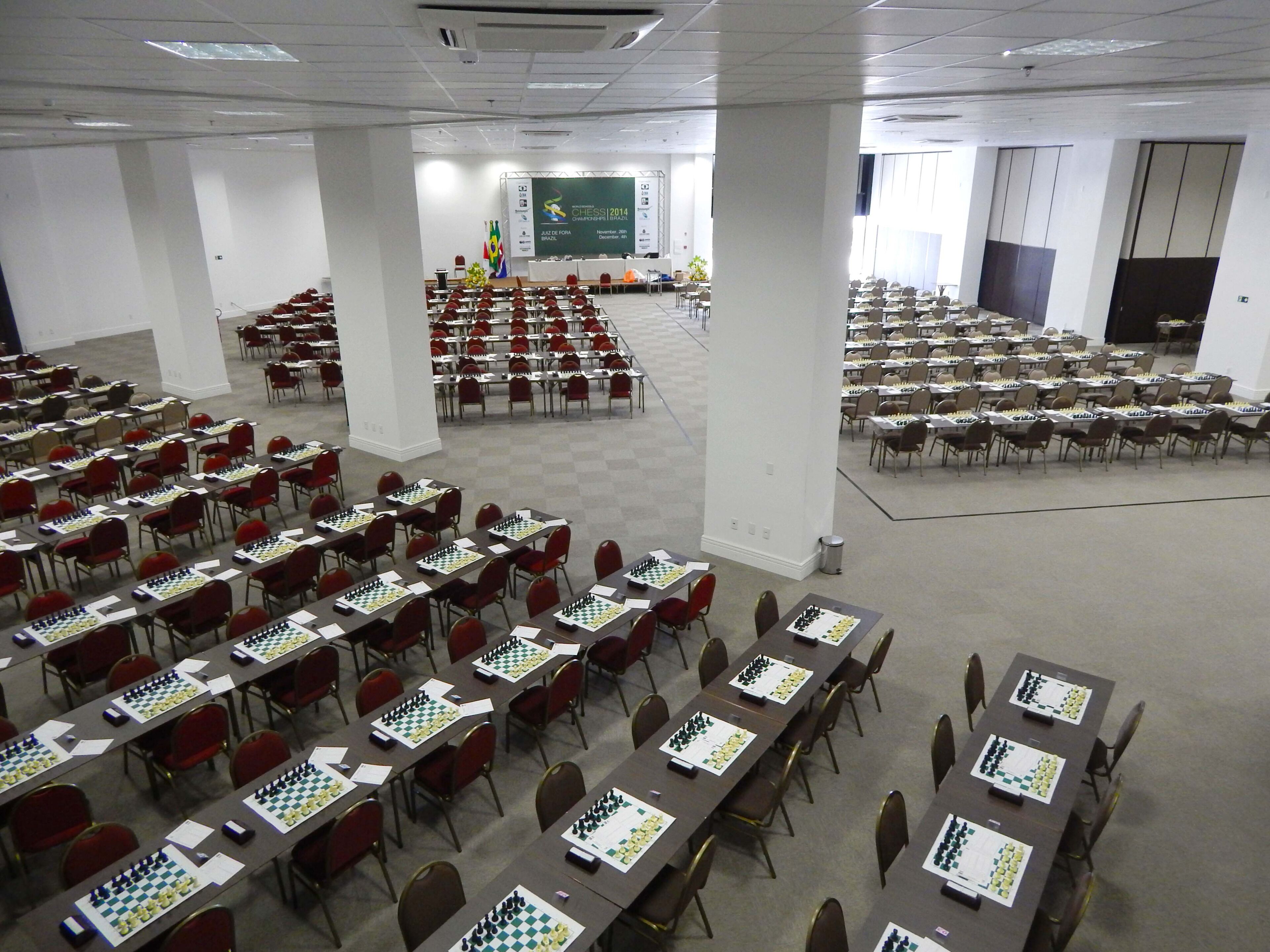 Une salle de conférence avec plusieurs tables disposées pour accueillir un tournoi d’échecs.