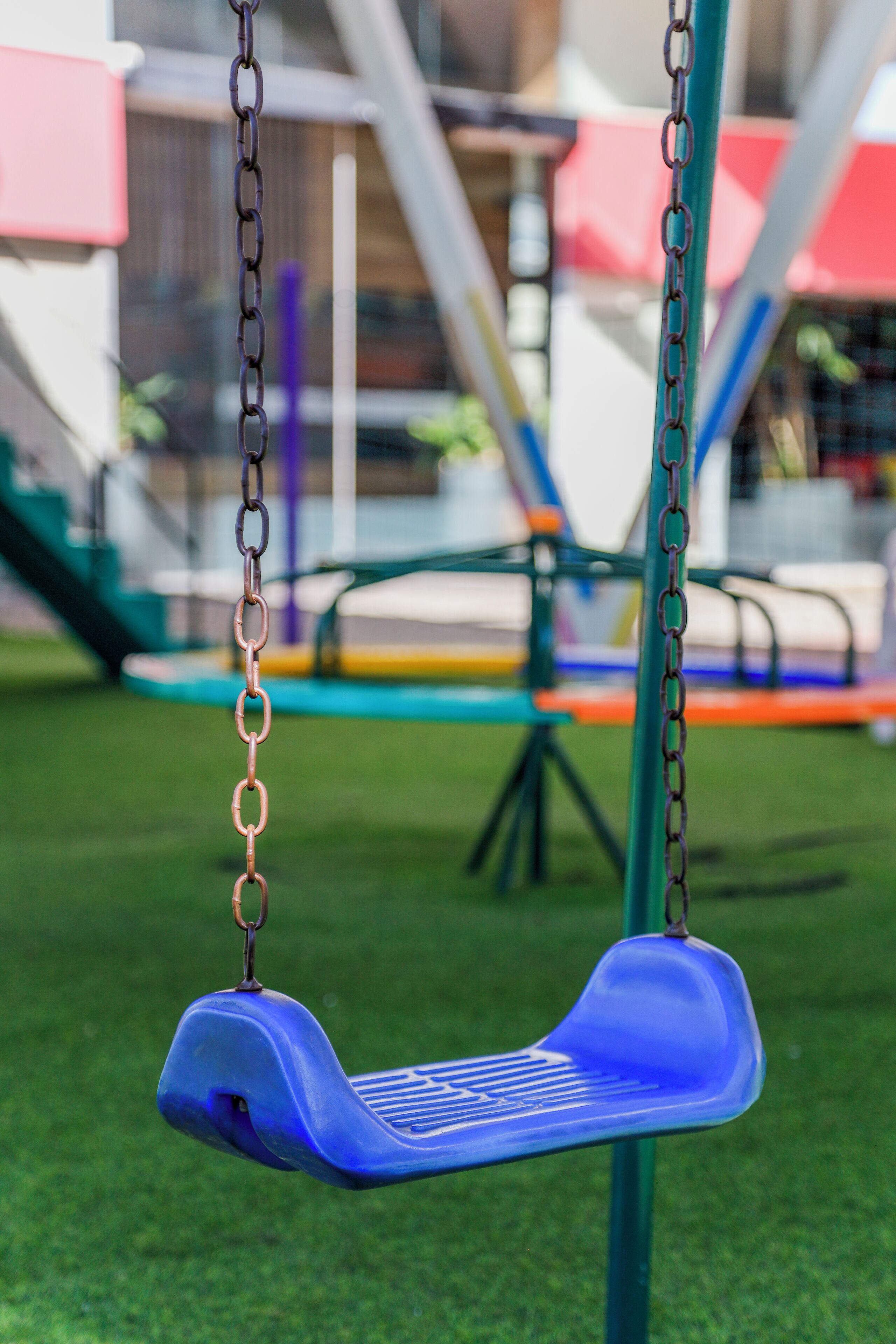 A blue swing set on a green artificial turf.