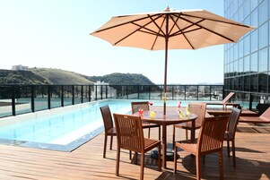 Una piscina al aire libre, sillones reclinables de piscina