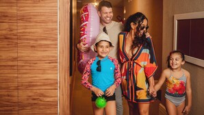 A family in a hallway with wooden walls and a door on the right. - Trade Hotel (Juiz de Fora)
