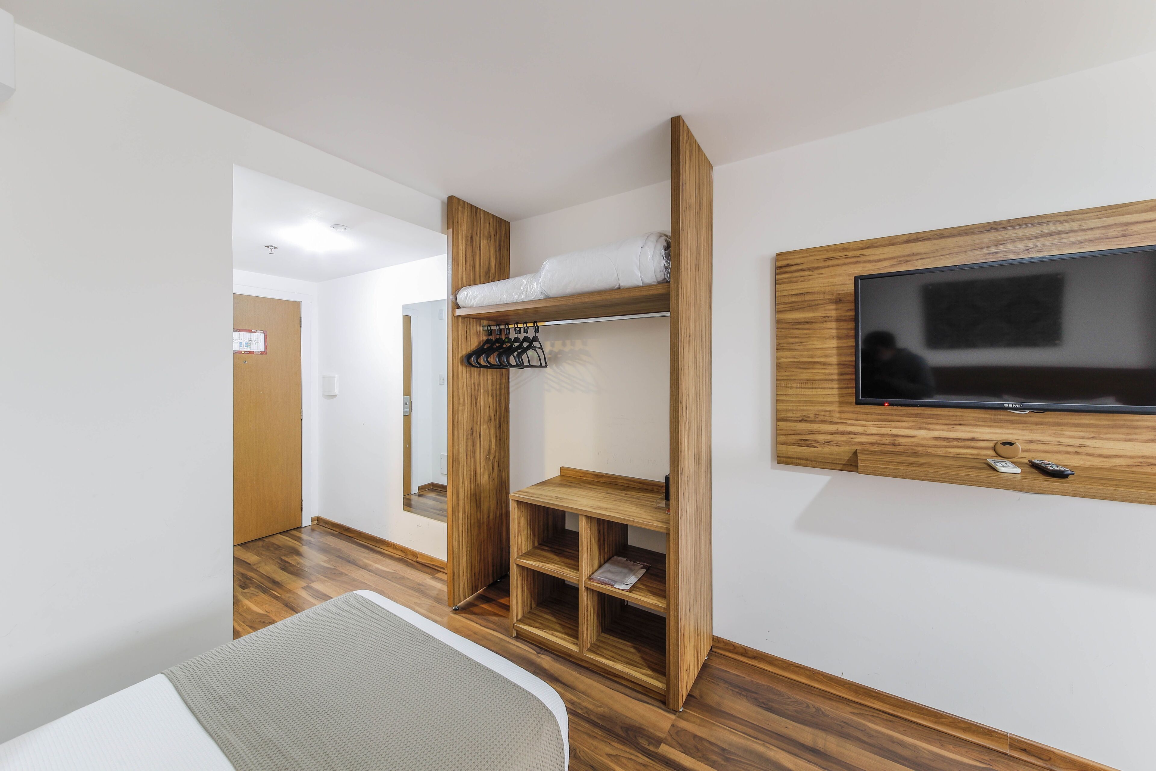 Ein Zimmer mit einem Etagenbett, einem an der Wand befestigten Fernseher und einem Holzschrank.