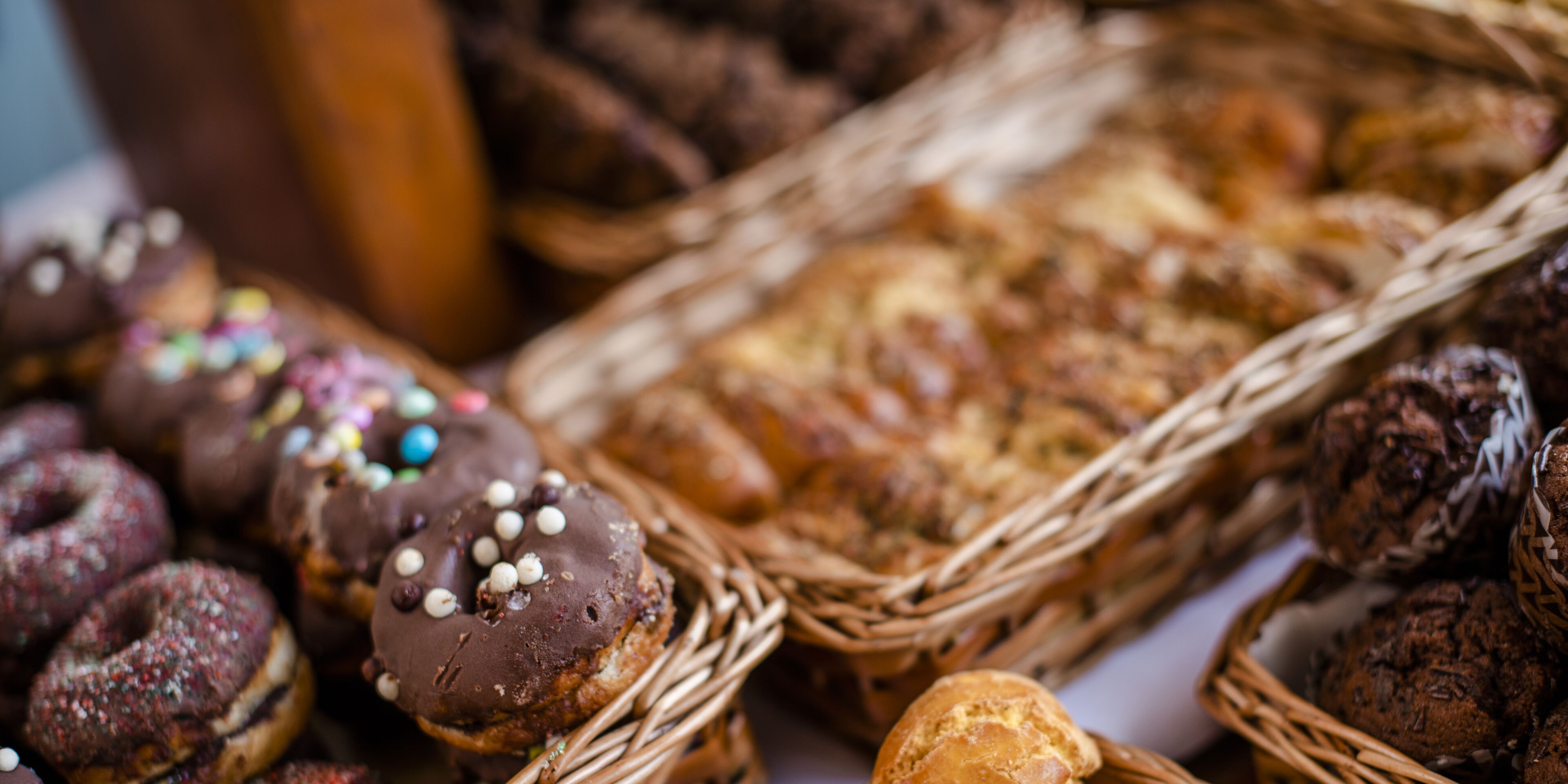 A variety of baked goods, including donuts and pastries, arranged in wicker baskets.
