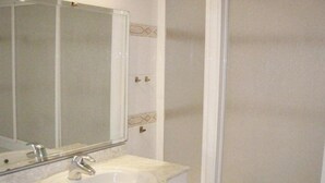 Een badkamer met een wastafel, spiegel en douche.