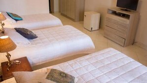 A hotel room with two beds, a television, a small cabinet, and a bedside table with a lamp. - Asuncion House (Asunción)