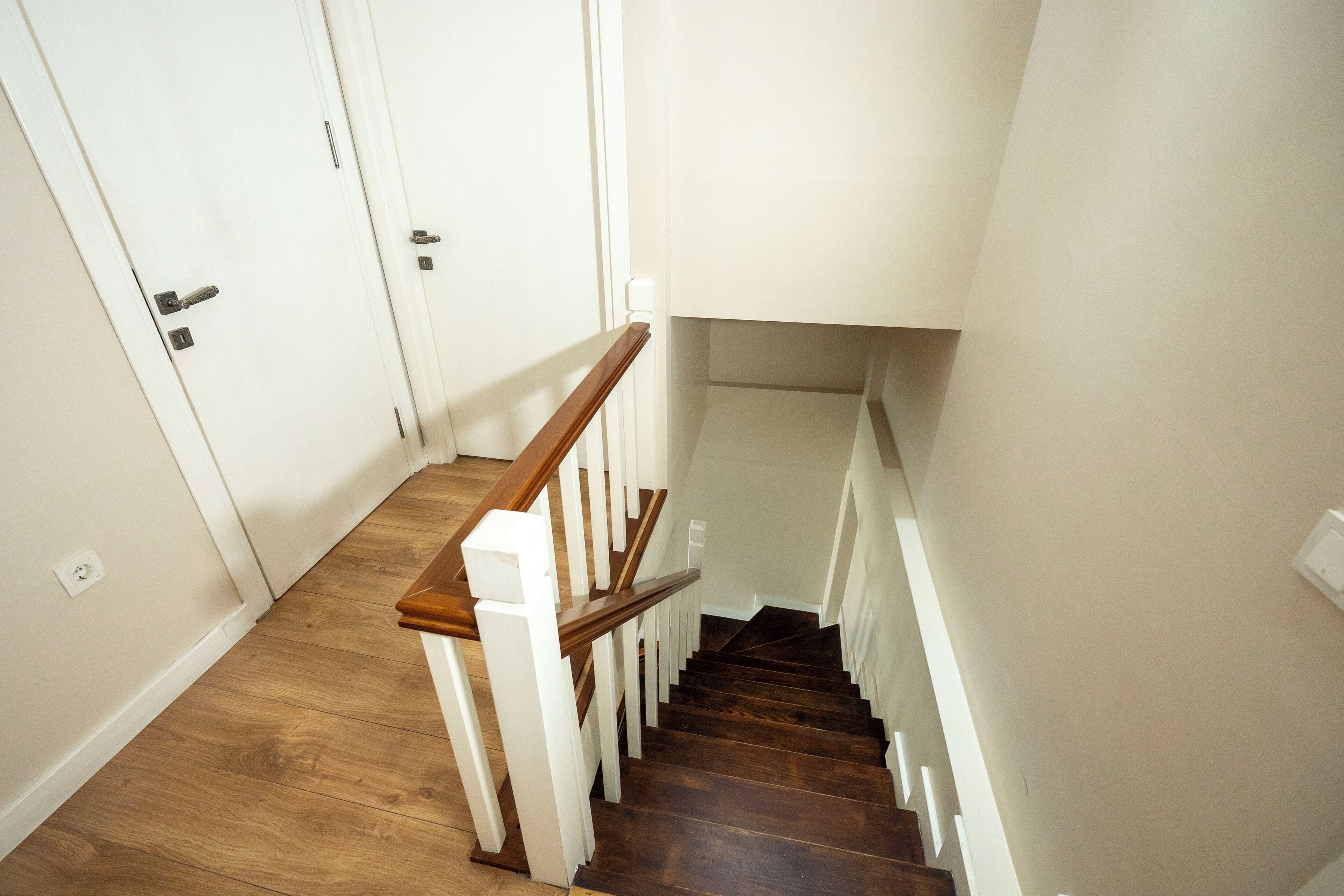 A wooden staircase with white railings leading to a landing.