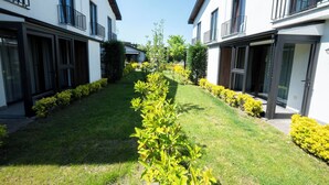 Une cour intérieure avec un chemin central bordé de haies et de petits arbres soigneusement taillés.