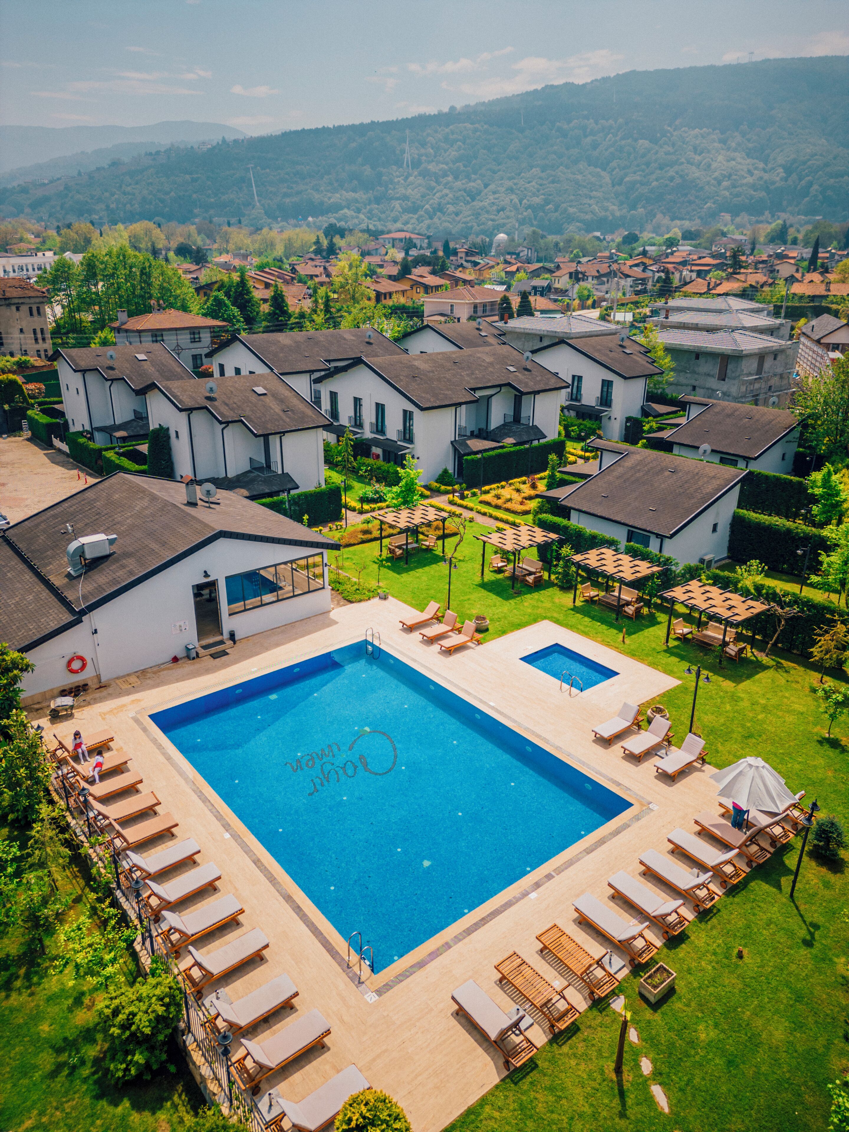 A residential area with a large swimming pool surrounded by lounge chairs and a garden.