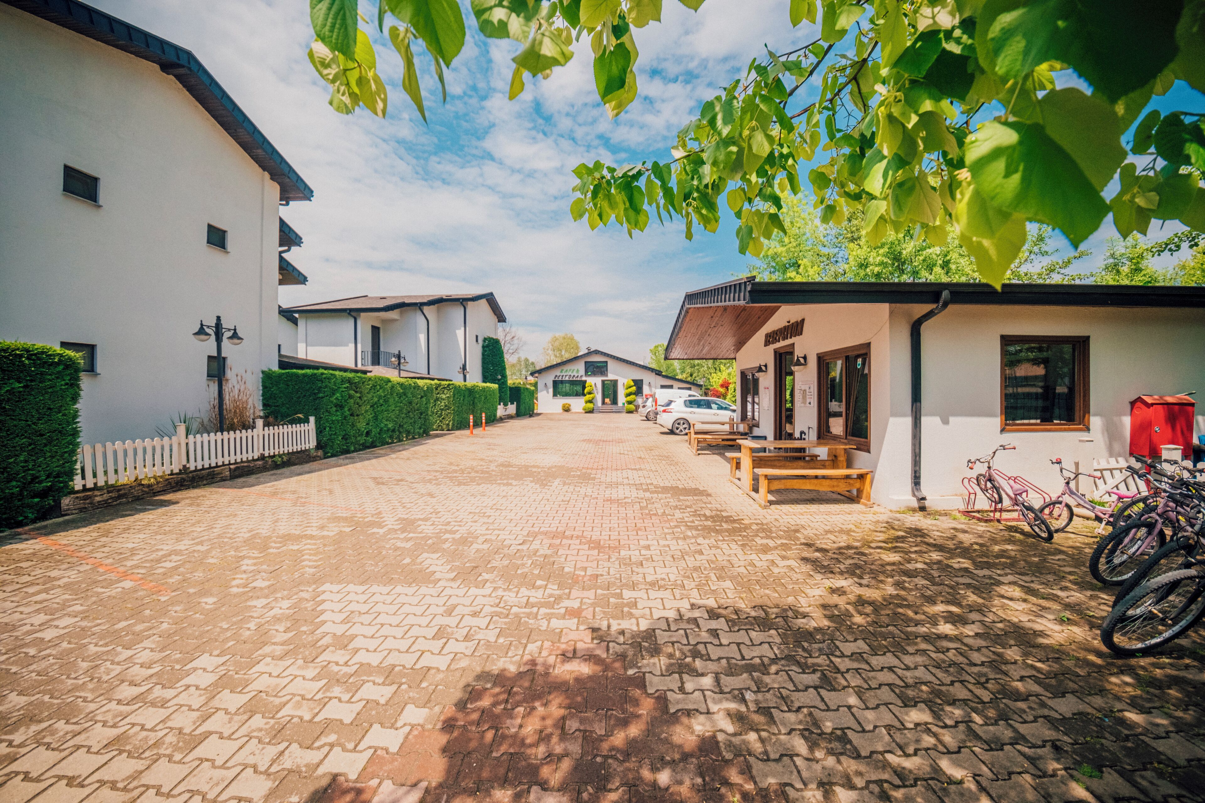 A paved driveway leading to a row of houses with bicycles parked outside.