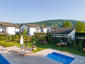 A residential area with a swimming pool, lounge chairs, and a garden.