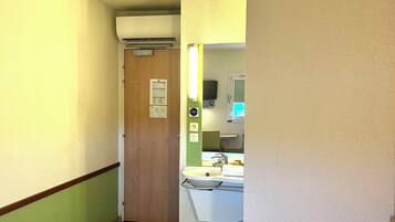 Habitació d'hotel amb llit, bany amb mànega i mirall, i una porta que condueix a una altra habitació.