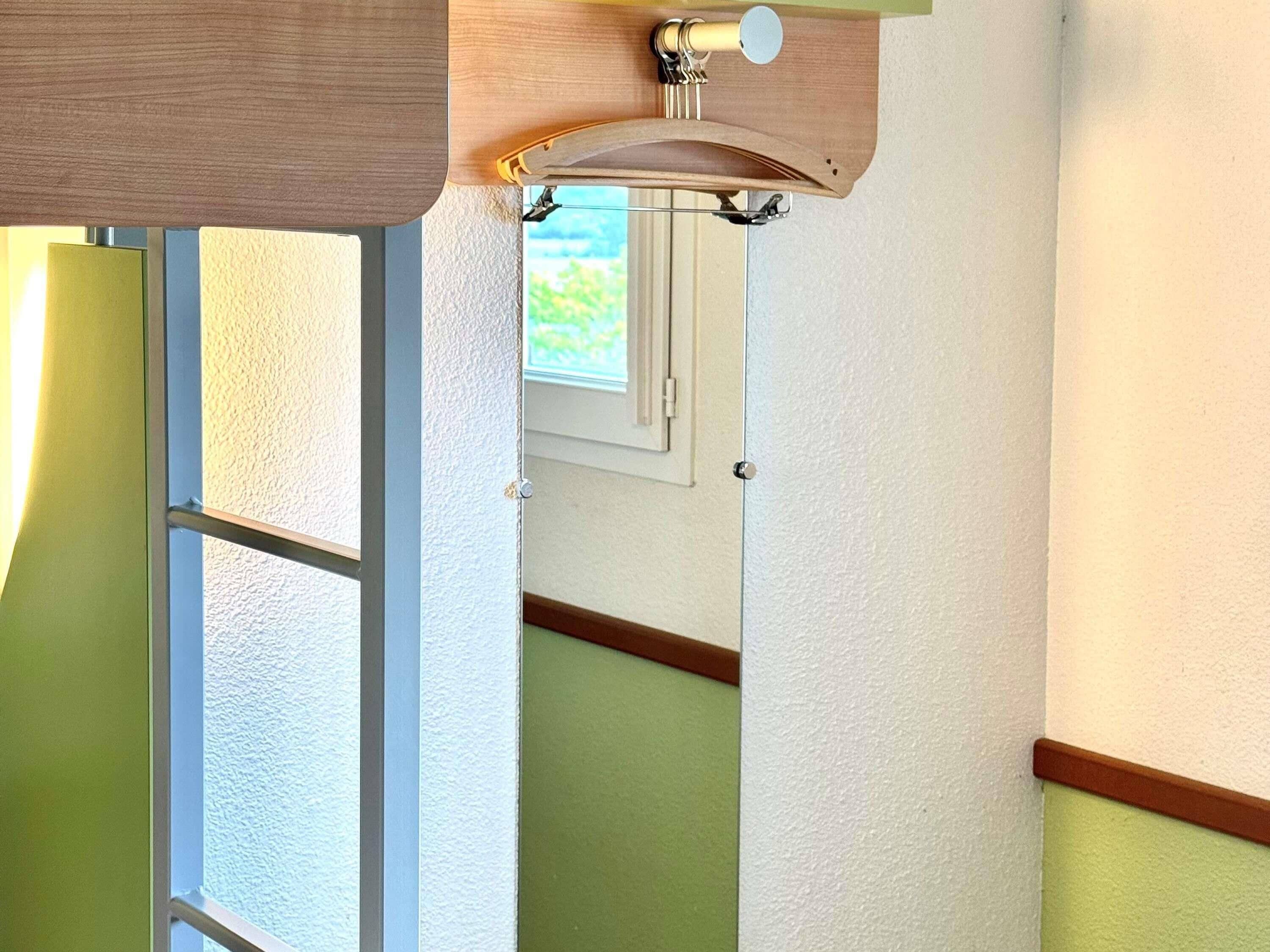 A room with a wooden ceiling, a white wall, and a window with blinds.