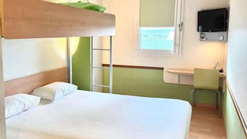 Een enkel bed met houten hoofdbord, een groene wand, een raam met uitzicht, een televisie boven het raam en een klein bureau met stoel.