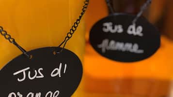 A close-up of a candle with a black tag labeled 'Jus d'orange' and another tag labeled 'Jus de flamme'.