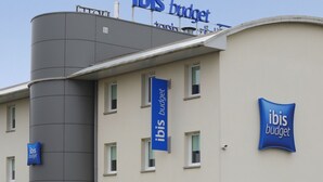 A building with 'ibis budget' signage on the facade, featuring a modern architectural design with a cylindrical structure and multiple windows. - ibis budget Cosne-sur-Loire (Cosne-Cours-sur-Loire)