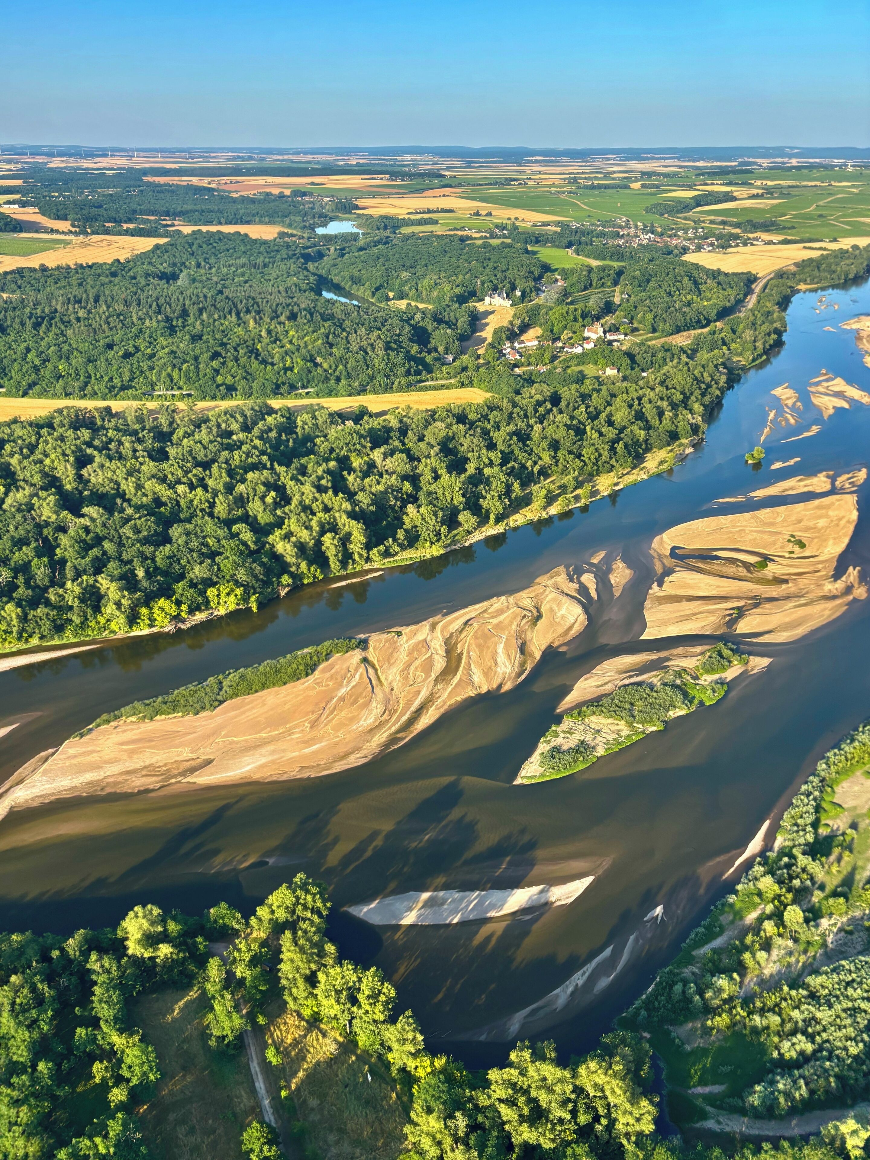 A river meandering through a landscape with dense forests and fields.