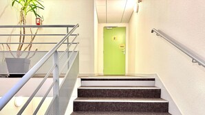 A staircase with metal railings, a green door, and a plant. - ibis budget Cosne-sur-Loire (Cosne-Cours-sur-Loire)