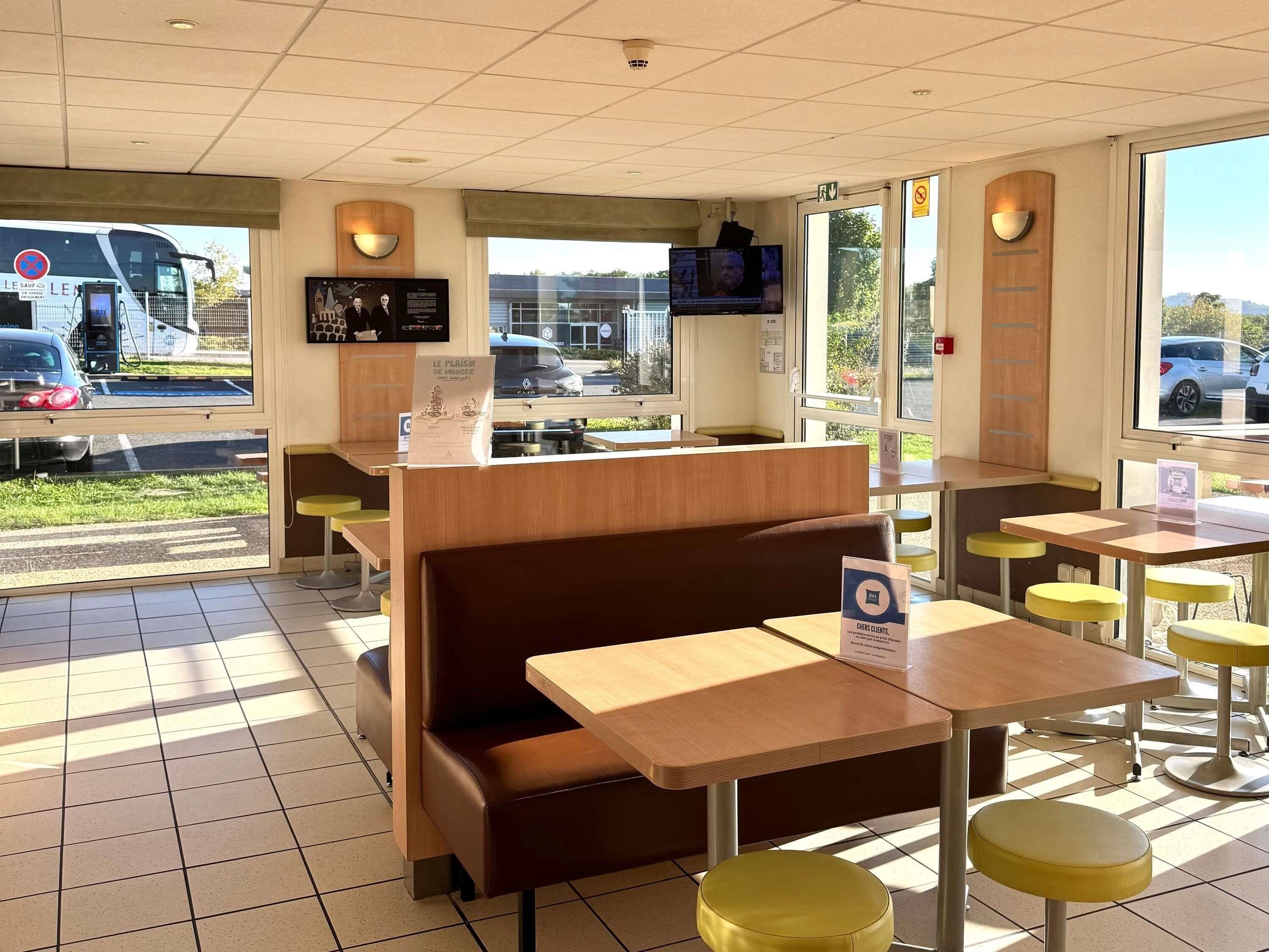 A restaurant interior with booths, tables, and a TV screen.