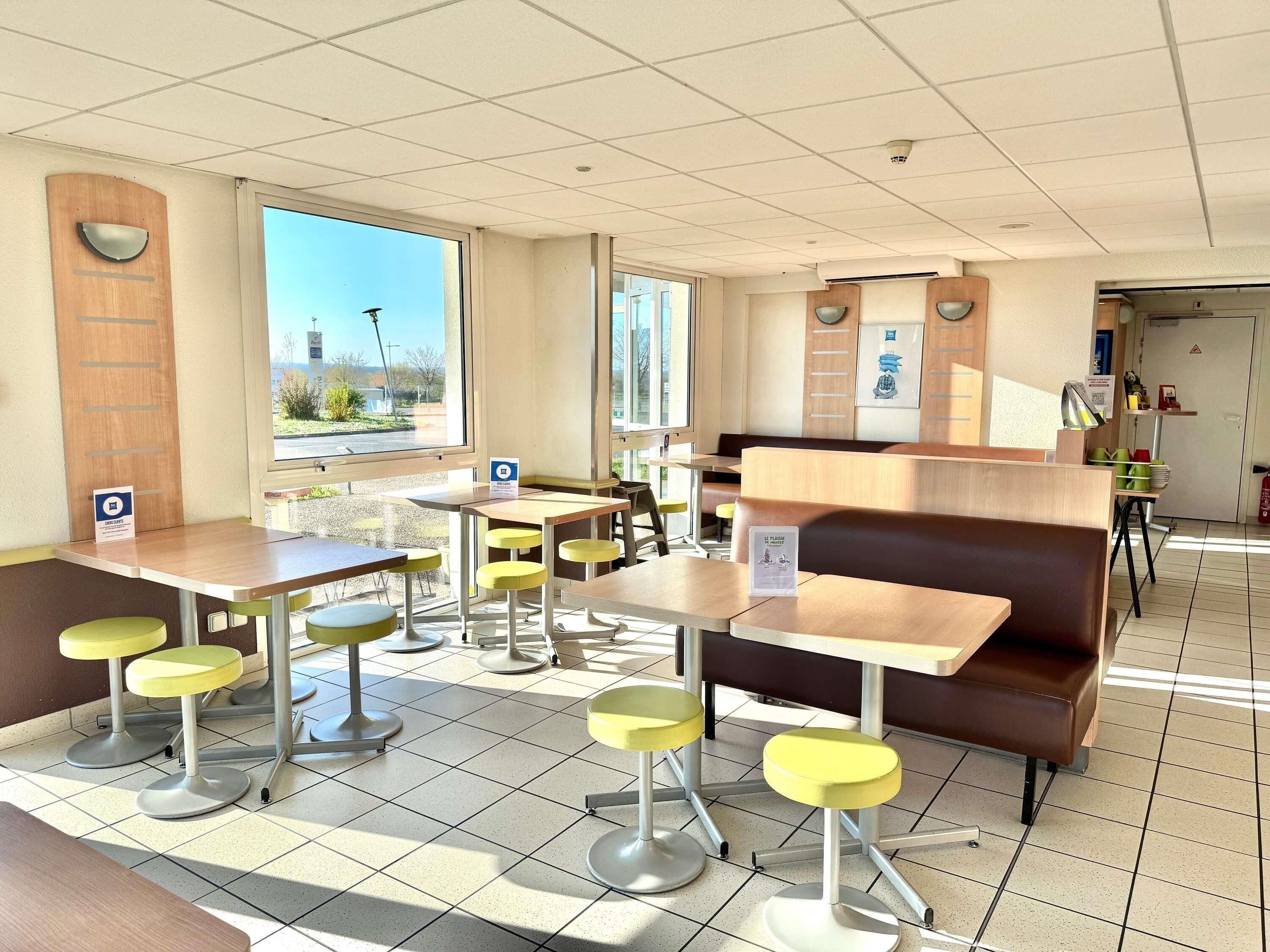 A restaurant with booths, high tables, and yellow stools.