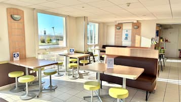 A restaurant with booths, high tables, and yellow stools.