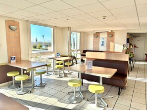 Un restaurante con cabinas, mesas altas y taburetes amarillos.