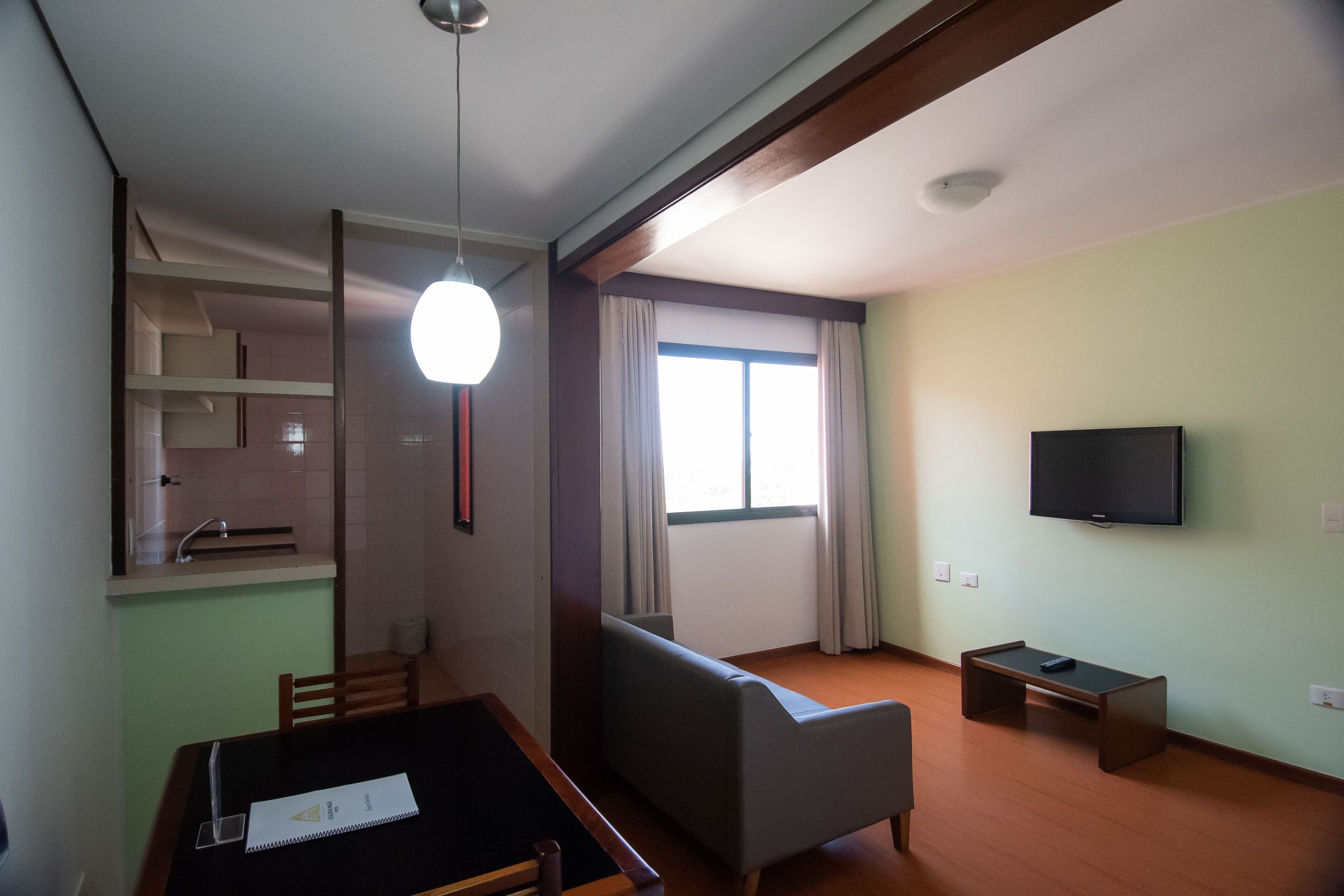 Una habitación con una mesa de comedor, un sofá, un televisor y una ventana con cortinas.