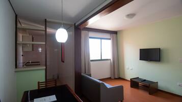 Una habitación con una mesa de comedor, un sofá, un televisor y una ventana con cortinas.