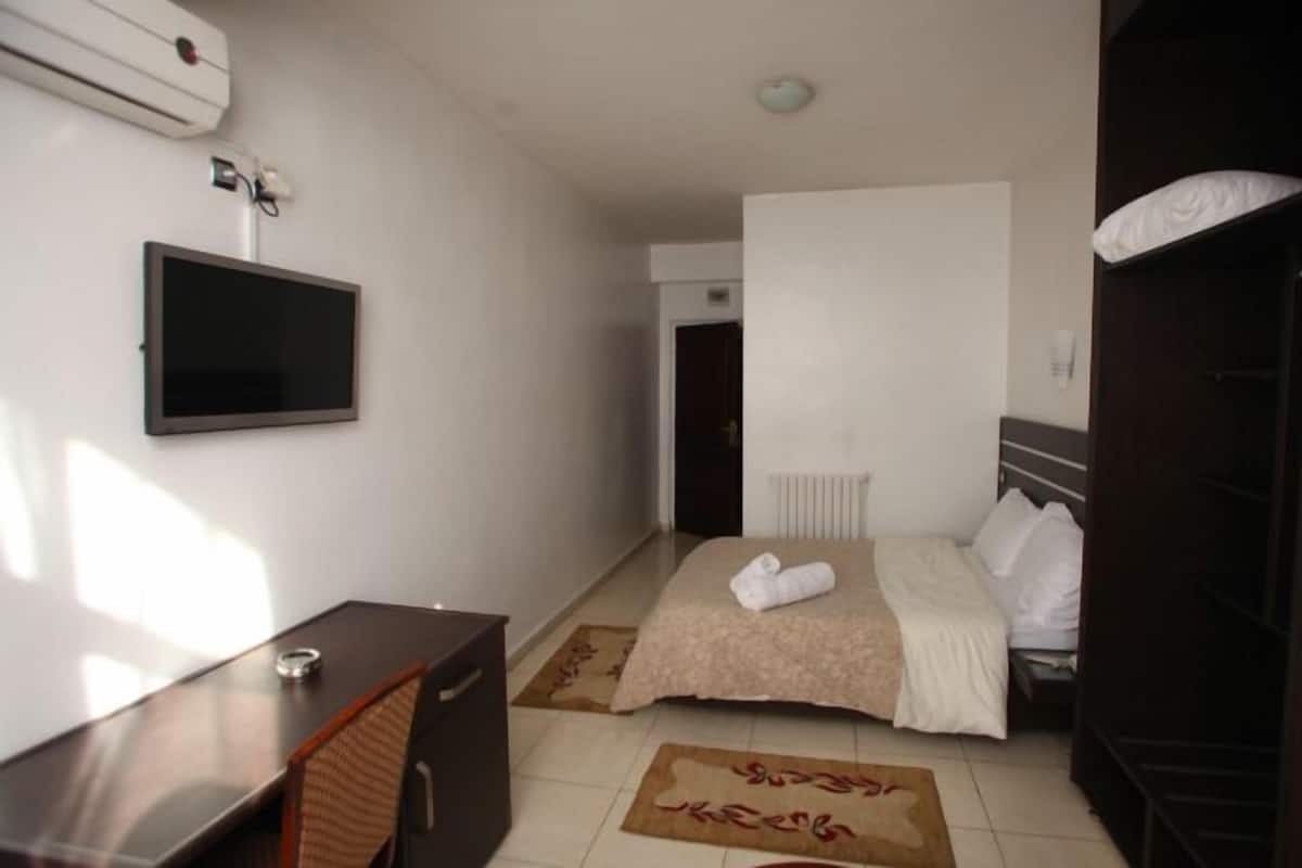 Ein Hotelzimmer mit Bett, Schreibtisch, Fernseher und Heizkörper.