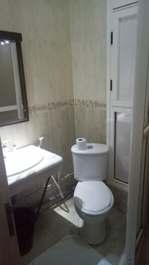 Une petite salle de bain avec des toilettes, un lavabo et un miroir.