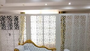 Une chambre luxueuse avec un canapé blanc et doré, un paravent décoratif blanc et une table basse en verre.