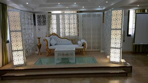 Une chambre luxueuse avec un canapé blanc, une petite table basse blanche et des paravents décoratifs aux motifs géométriques.