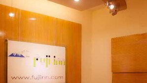 A reception area with a wooden panel wall, a reception desk, and a sign with a website URL. - Fuji Inn (GULSHAN 1)