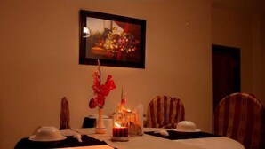 A dining table set for two with a candle, a vase of flowers, and a framed picture above. - Fuji Inn (GULSHAN 1)