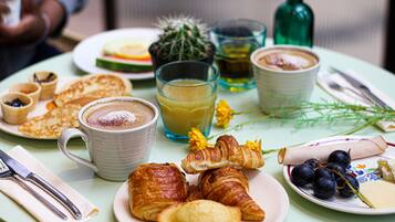 Mesa de pequeno-almoço com croissants, uma chávena de café e um prato de mirtilos.