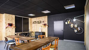 A room with wooden walls, a large table, several chairs, a bicycle, and a door. - Greet Hotel Evreux Centre - Route de Normandie by Accor (Evreux)