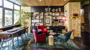 A cozy reading area with bookshelves, comfortable seating, and a large window providing natural light. - Greet Hotel Evreux Centre - Route de Normandie by Accor (Evreux)