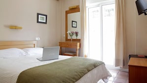 A hotel room with a bed, a desk with a laptop, a mirror, and a TV. - Pella (Thessaloniki)