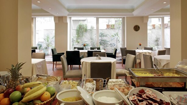 A breakfast buffet with various food items and a dining area with tables and chairs. - Pella (Thessaloniki)