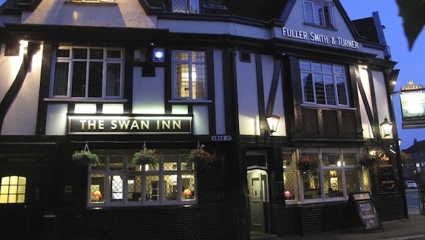 Un edificio de estilo Tudor tradicional con el letrero "The Swan Inn", que alberga un pub y habitaciones.