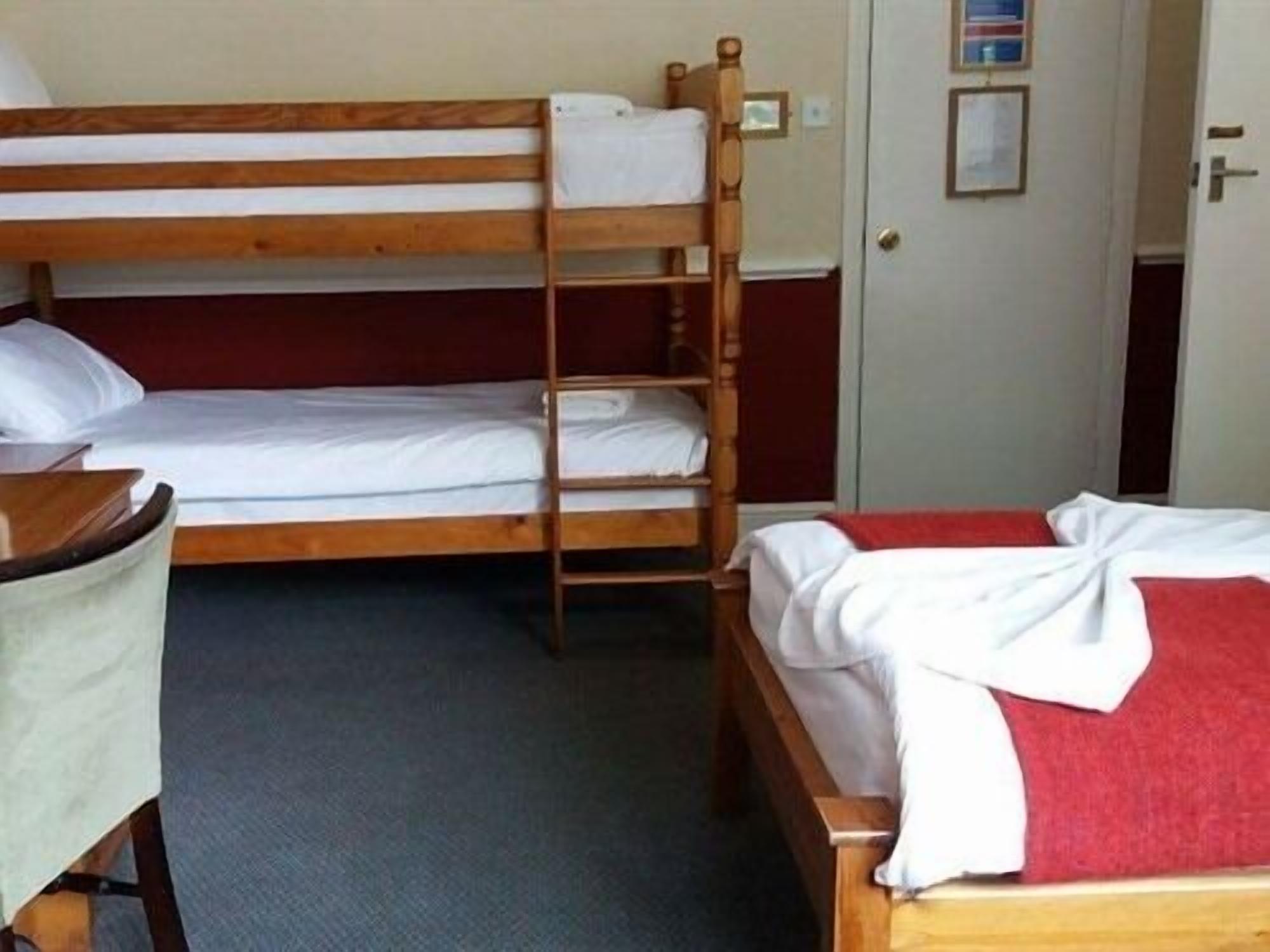 A bunk bed room with a desk and chair, a door, and a framed picture on the wall.