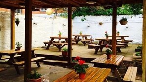 Un patio al aire libre con mesas de picnic de madera y plantas en macetas.