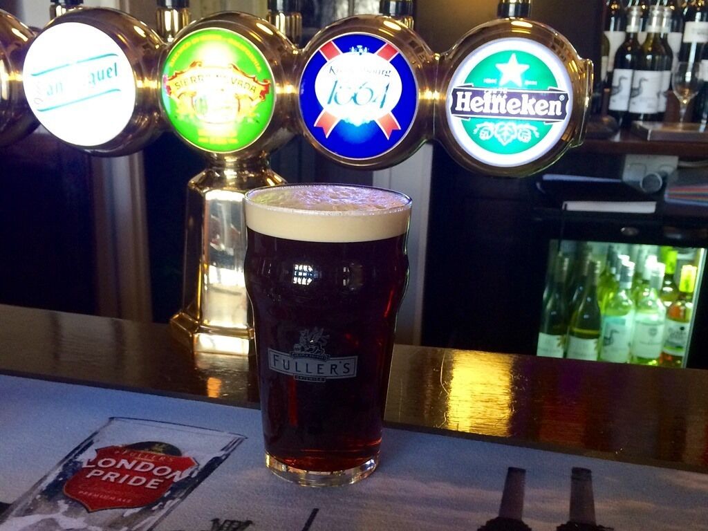 A bar with beer taps and a glass of beer.