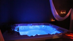 A hot tub with a blue light, a plant, and a draped curtain.